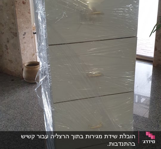ארון מגירות עטוף בניילון על עגלת הובלה